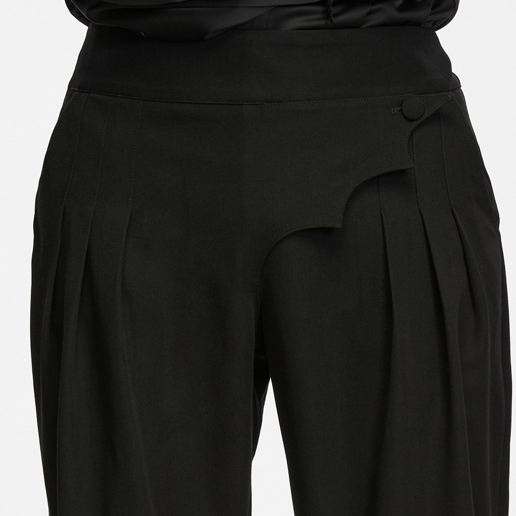 Close-up detail view of the Punk Rave Ink Ruins Batwing Pleated Trousers (WK-839DQM), highlighting the unique scalloped batwing waist flap, decorative button fastening, and structural 3D hip pleating